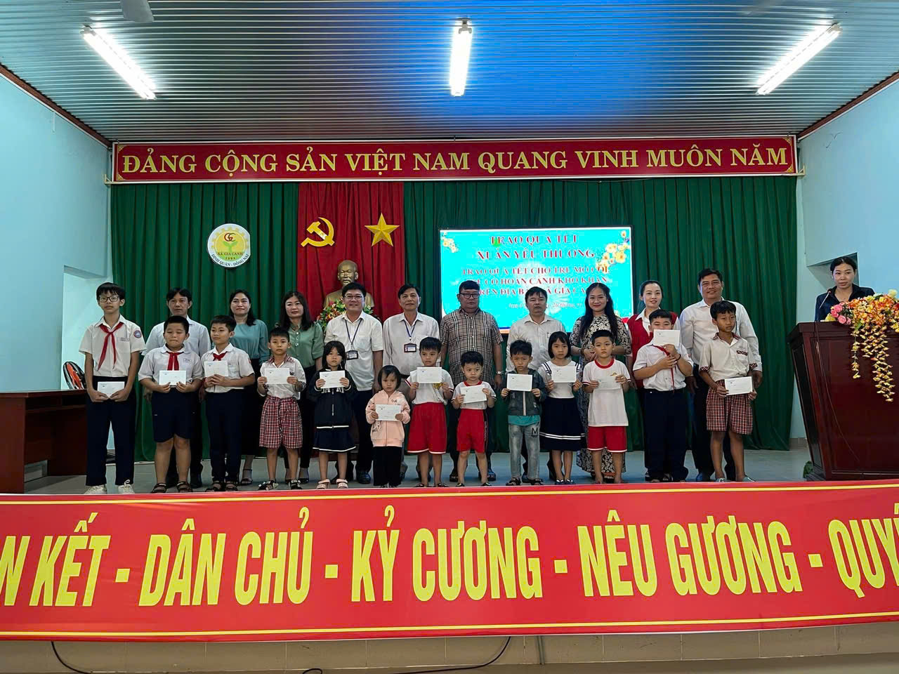 Hình 4. Các lãnh đạo xã cùng các nhà tài trợ trao quà và chụp hình với các em học sinh có hoàn cảnh khó khăn.jpg